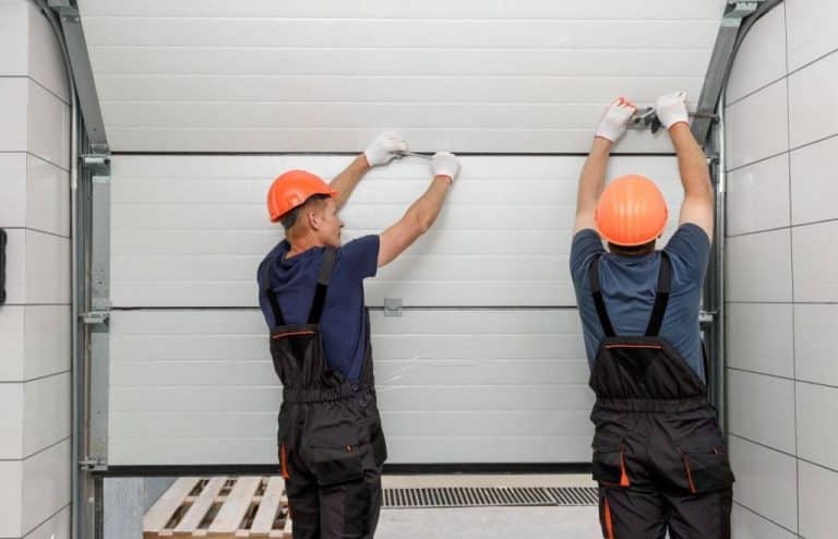 Two workers installing a garage door.