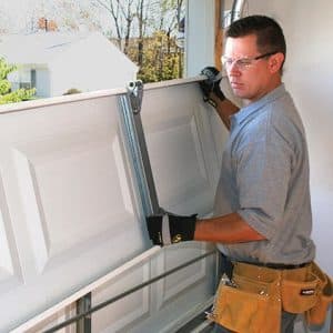 Man repairing garage door panel.