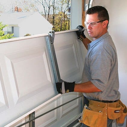 Man repairing garage door panel.